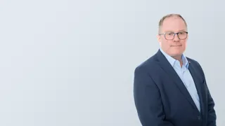 Porträtbild mit grauem Hintergrund von Dr. Thomas Hausner