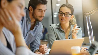 Drei Personen arbeiten in einem Büro im Team.