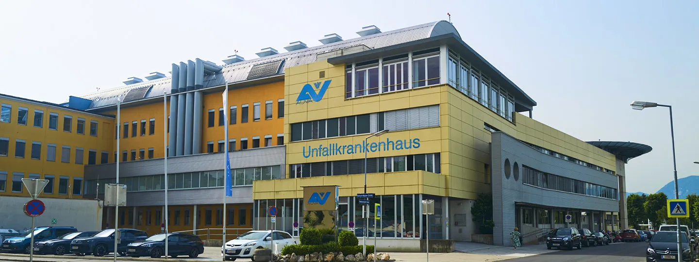 Außenansicht UKH Klagenfurt am Wörthersee, umgeben von geparkten Autos und Straße. Außenansicht UKH Klagenfurt am Wörthersee, umgeben von geparkten Autos und Straße.