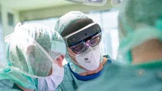 Ärzte während einer Operation, einer von ihnen trägt eine VR-Brille  Ärzte während einer Operation, einer von ihnen trägt eine VR-Brille