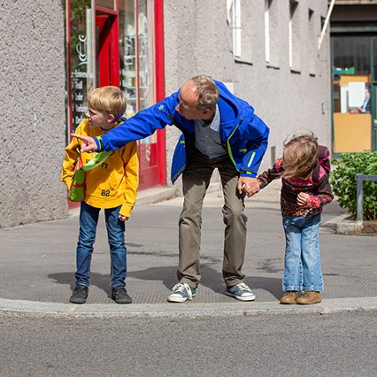 Mann mit Kindern bei der Straßenüberquerung (Symbolbild)
