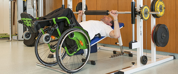 Patient im Rollstuhl beim Gewichtstemmen