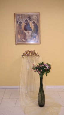 Ikonenbild, davor Kerzen und Blumen