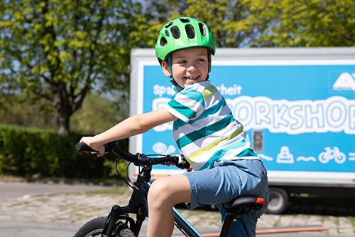 Kind mit Helm auf Fahrrad beim Schulterblick