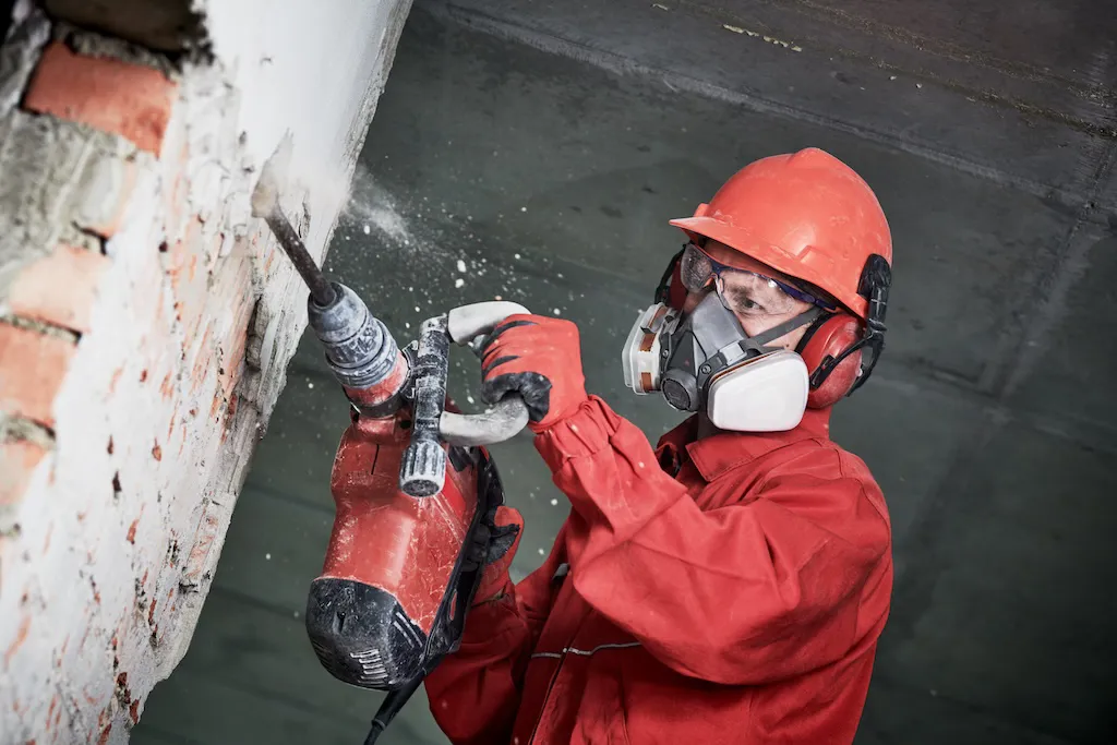 4.1.2.10_Lärm_AdobeStock_236846144.jpeg Arbeiter mit Gehörschutz beim Stemmen.