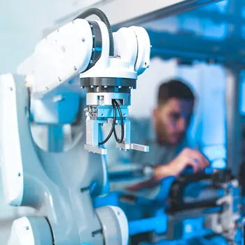 Im Vordergrund ein Roboter im Hintergrund das verschwommene Bild eines Mannes Im Vordergrund ein Roboter im Hintergrund das verschwommene Bild eines Mannes