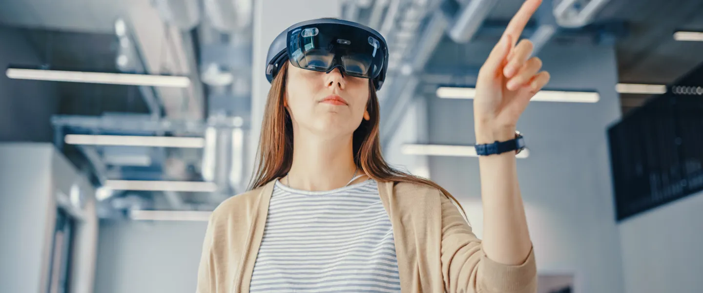 Frau interagiert mit VR-Brille Frau arbeitet im Büro mit VR-Brille.