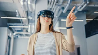 Frau interagiert mit VR-Brille Frau arbeitet im Büro mit VR-Brille.