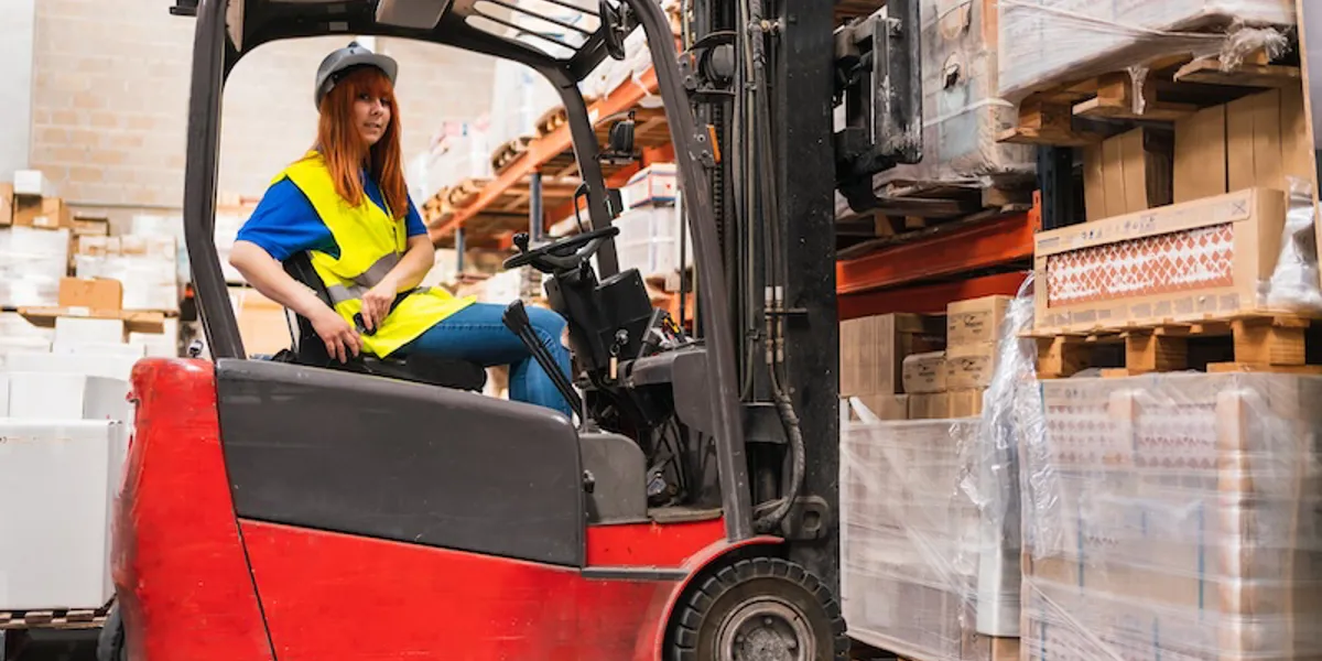 Junge Frau im Gabelstapler Junge Frau im Gabelstapler schnallt sich an.